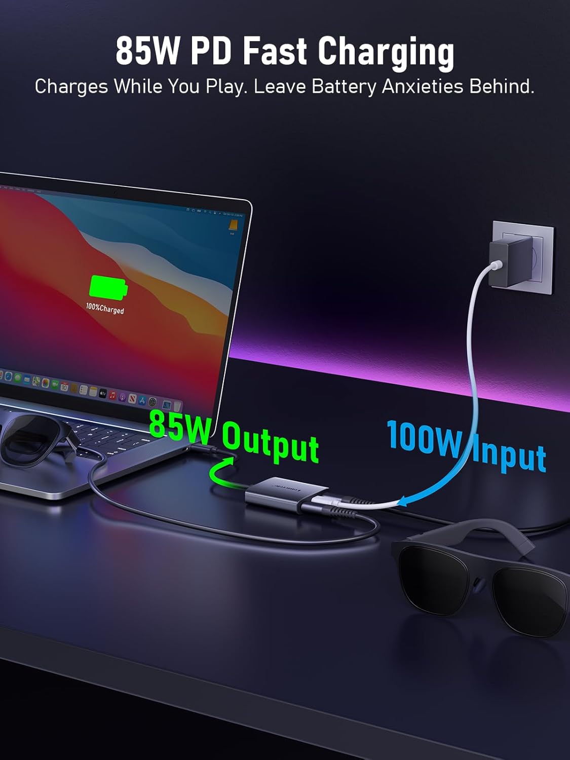 Laptop with charging cable, sunglasses, and power outlet on a dark surface with text about 85W PD fast charging.