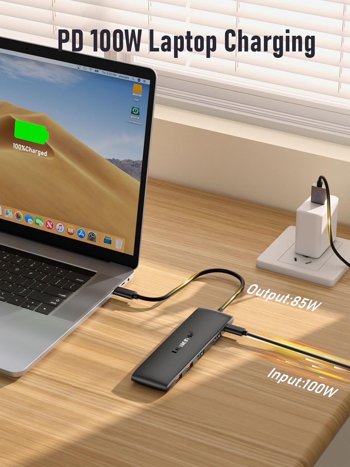 Laptop charging with a power adapter on a wooden desk
