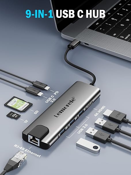 9-in-1 USB C hub connected to a laptop with various cables and devices on a gray background.