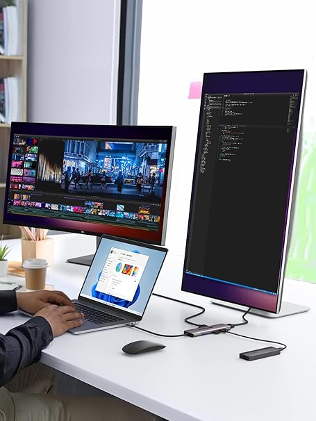 Person using a laptop with two monitors on a desk, one displaying a video editing software and the other showing code.