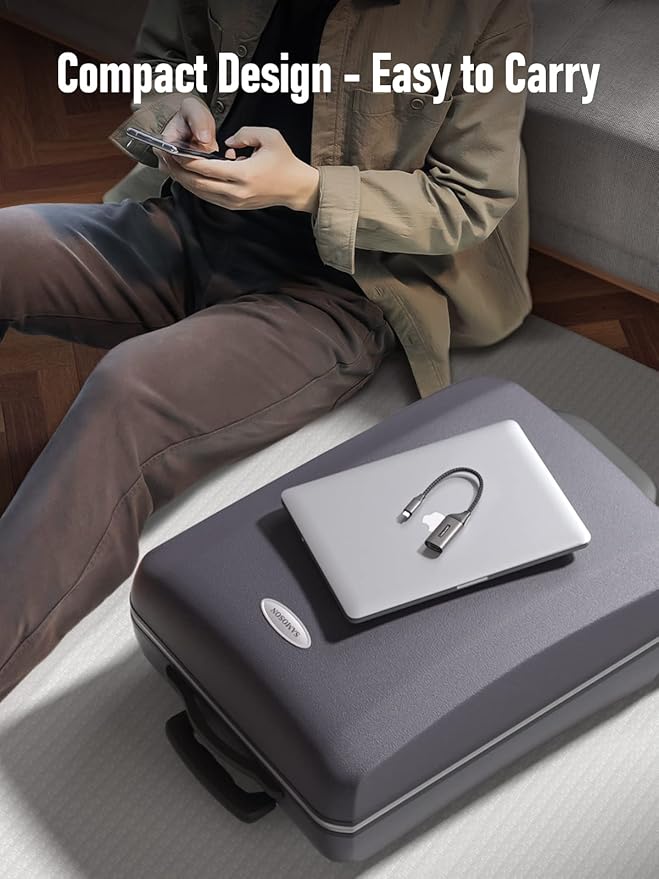 Person sitting on a couch with a compact suitcase next to them, featuring a laptop and cable.