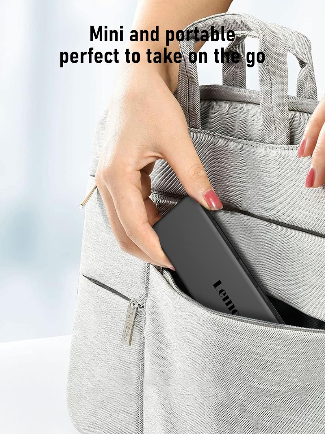Person holding a gray backpack with a laptop inside, text 'Mini and portable perfect to take on the go'.